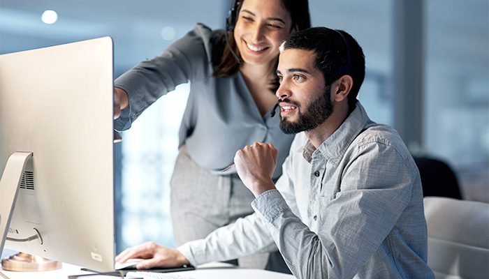 man sitting at the computer, woman coworker pointing at the screen.