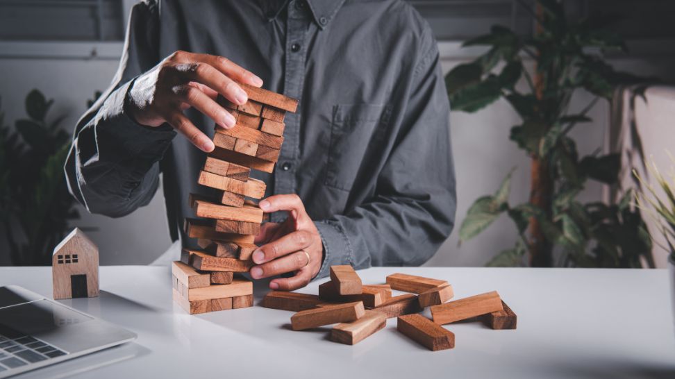 man holding falling tower of blocks