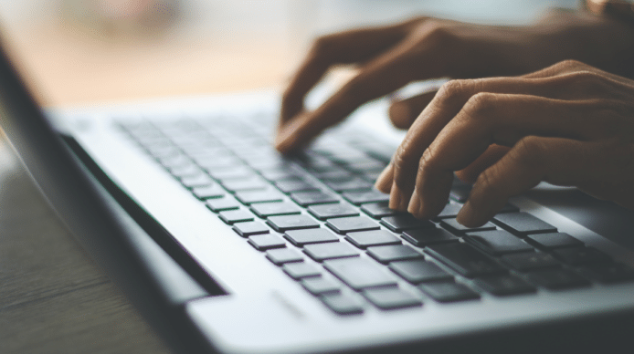 A laptop keyboard with a person's hands resting on the keys