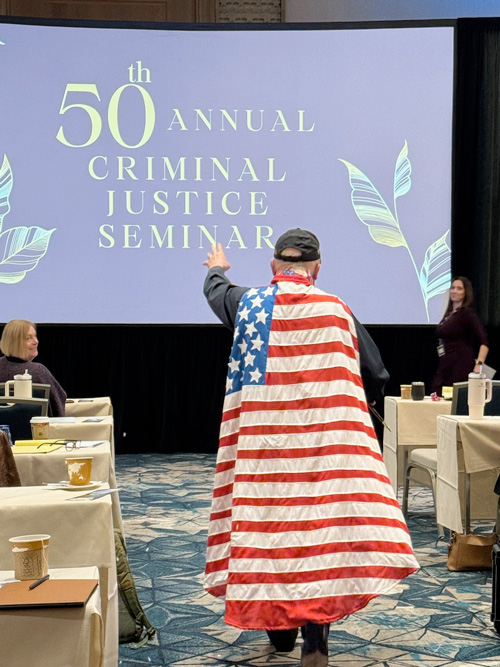Captain Motion (Michael Kennedy) approaches the stage at a seminar where he gives a speech about motions!
