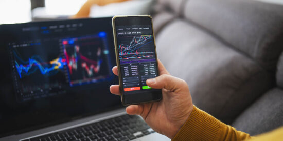 Man buying cryptocurrency at home via laptop and phone.