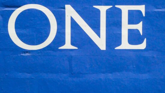 The word one in white on a blue brick wall.
