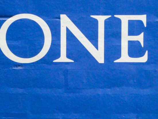 The word one in white on a blue brick wall.