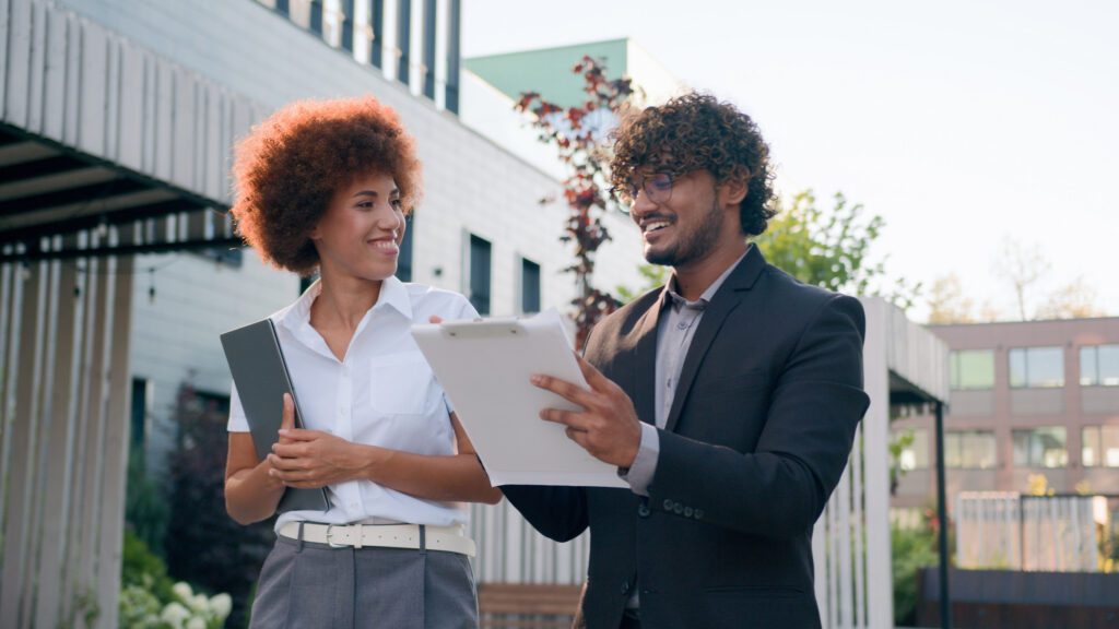 Diverse African American woman businesswoman and Hispanic Indian man Arabian businessman multiracial colleagues coworkers partners talking walking city downtown walk discuss document business papers. High quality 4k footage