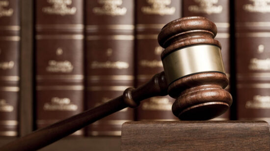 Gavel on wooden desk with books as background